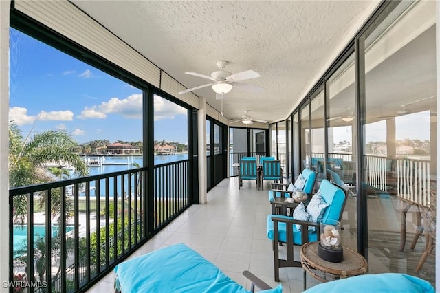 sunroom / solarium featuring a water view and ceiling fan