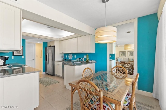 kitchen with white cabinets, sink, hanging light fixtures, light tile patterned floors, and stainless steel appliances