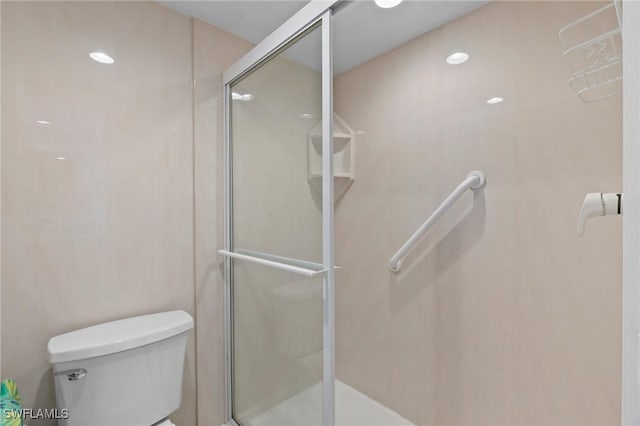 bathroom featuring a shower with shower door and toilet