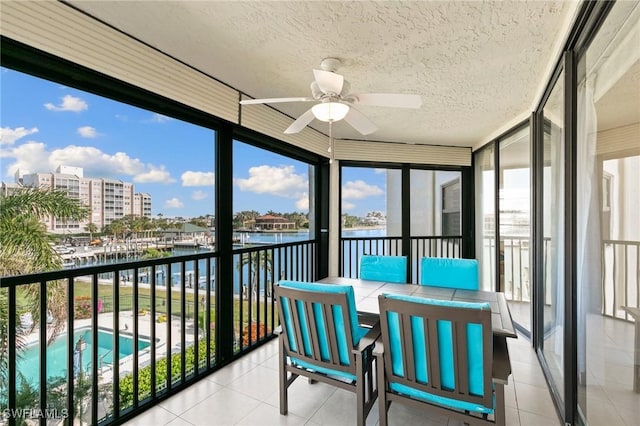 sunroom / solarium with a water view and ceiling fan