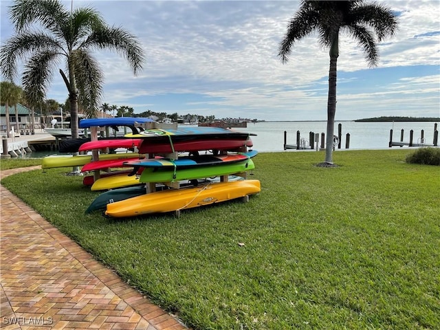 surrounding community with a water view and a lawn