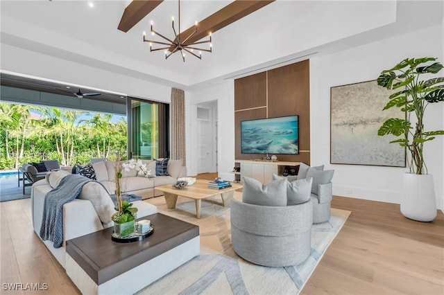 living room featuring ceiling fan with notable chandelier, light hardwood / wood-style floors, beam ceiling, and a high ceiling