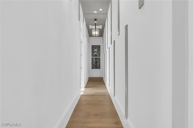 hallway with a chandelier and light hardwood / wood-style floors