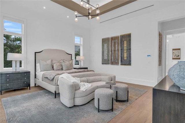 bedroom featuring a notable chandelier, wood-type flooring, and multiple windows