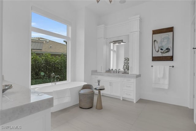 bathroom with tile patterned flooring, vanity, a washtub, and a wealth of natural light