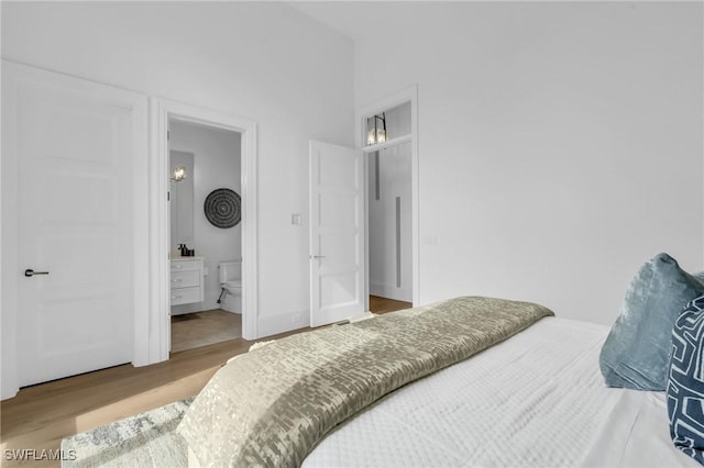 bedroom with connected bathroom and wood-type flooring