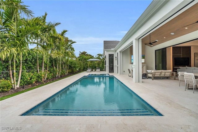 view of pool with an outdoor living space, ceiling fan, and a patio area