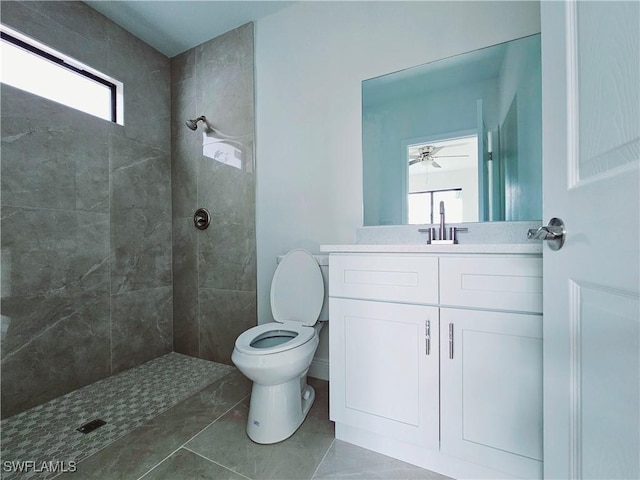 bathroom with a tile shower, vanity, and a healthy amount of sunlight