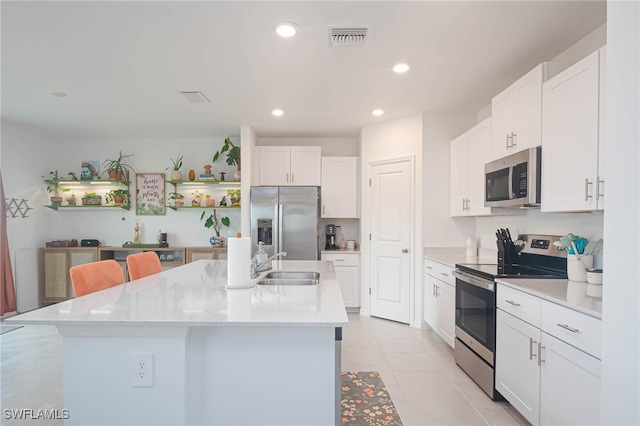 kitchen featuring appliances with stainless steel finishes, sink, a center island with sink, white cabinetry, and light tile patterned flooring