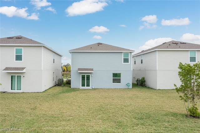 rear view of property featuring a lawn and central air condition unit