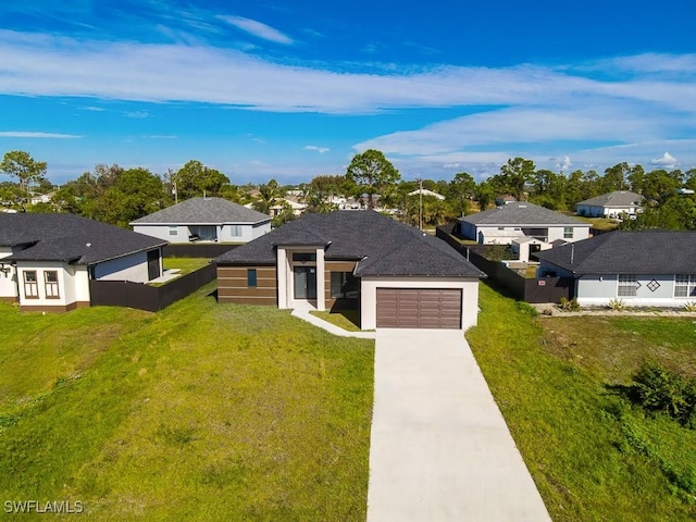 prairie-style home featuring an attached garage, fence, a residential view, driveway, and a front lawn