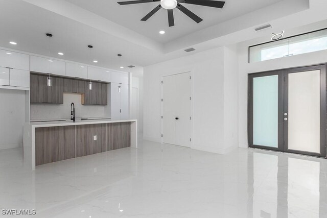 kitchen with visible vents, modern cabinets, light countertops, white cabinetry, and a sink