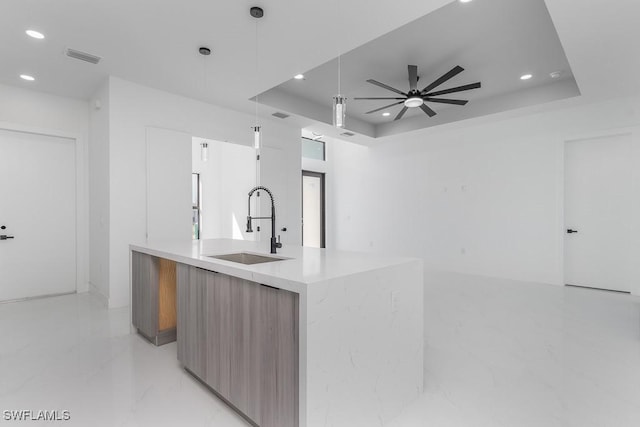 kitchen with a tray ceiling, a sink, recessed lighting, and modern cabinets