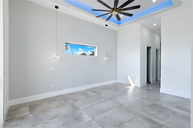 empty room featuring a tray ceiling and ceiling fan