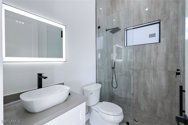 bathroom with tiled shower, vanity, and toilet