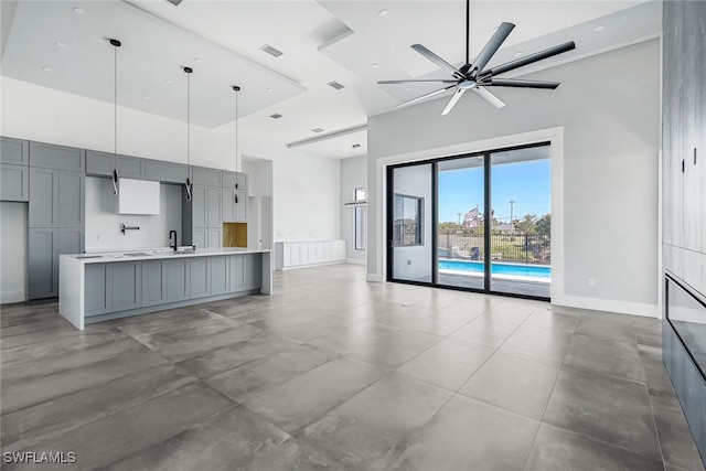 unfurnished living room featuring ceiling fan, sink, concrete floors, and a high ceiling