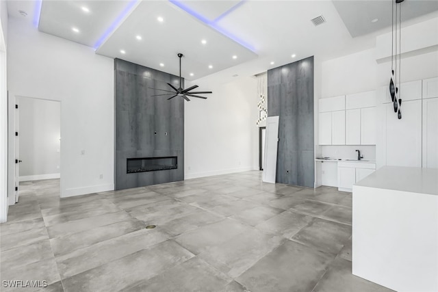 unfurnished living room with a high ceiling, a large fireplace, and ceiling fan