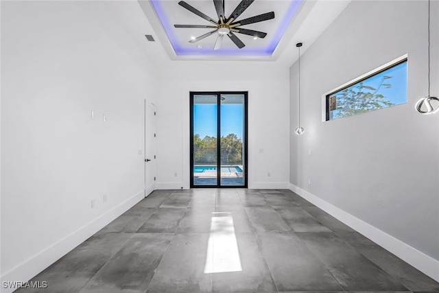 spare room with ceiling fan, a raised ceiling, a towering ceiling, and concrete floors