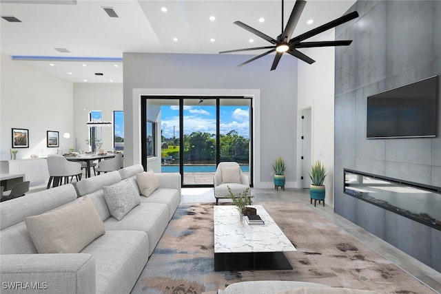 living room featuring ceiling fan, a large fireplace, concrete floors, and a high ceiling