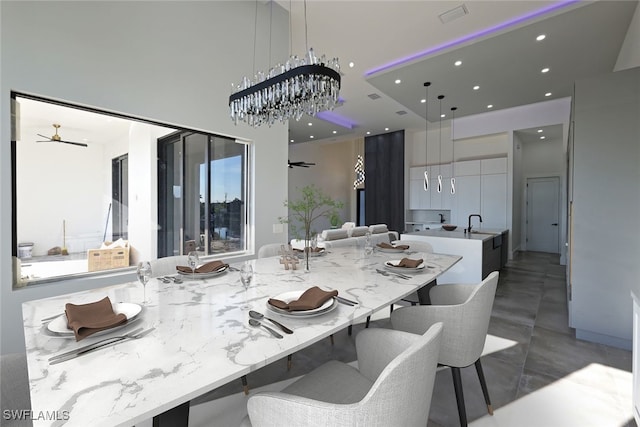 dining area featuring ceiling fan with notable chandelier and sink