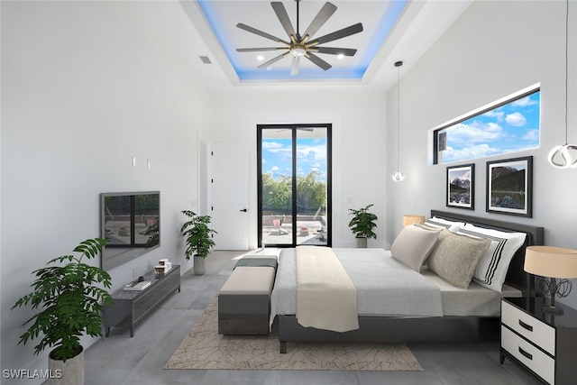 bedroom featuring ceiling fan, access to exterior, a towering ceiling, and a tray ceiling