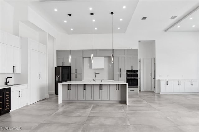kitchen featuring double oven, a high ceiling, a sink, and gray cabinetry