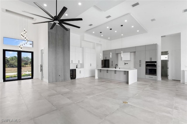 unfurnished living room featuring a high ceiling, a sink, visible vents, a ceiling fan, and french doors