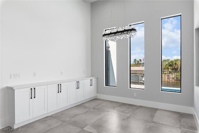 spare room featuring a notable chandelier and baseboards
