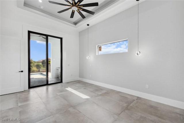 spare room with a ceiling fan, a tray ceiling, a towering ceiling, and baseboards