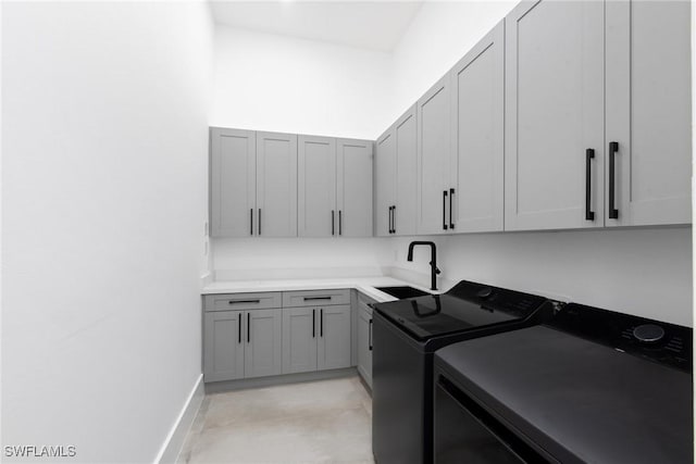 washroom featuring cabinet space, washing machine and dryer, baseboards, and a sink