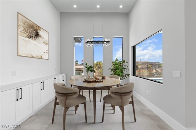 dining room featuring baseboards, recessed lighting, a towering ceiling, and an inviting chandelier