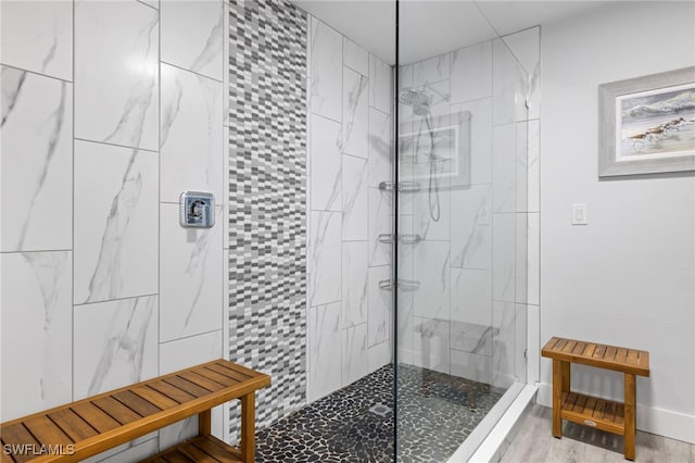 bathroom with a tile shower and hardwood / wood-style floors