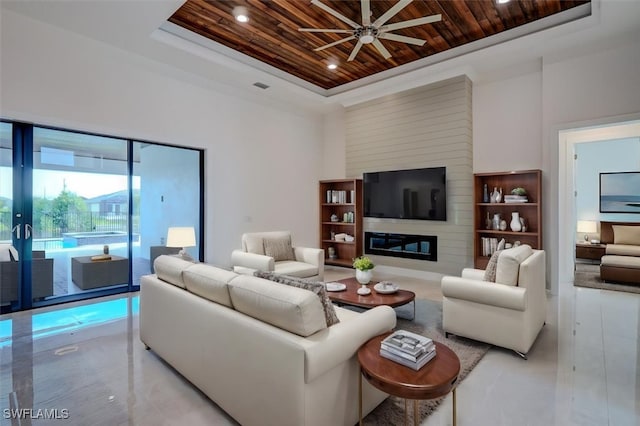 living room featuring a large fireplace, a raised ceiling, ceiling fan, and wood ceiling