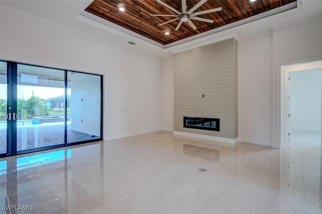 unfurnished living room with ceiling fan, wooden ceiling, a fireplace, and a tray ceiling