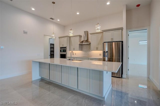 kitchen featuring hanging light fixtures, wall chimney exhaust hood, gray cabinets, a large island, and stainless steel appliances