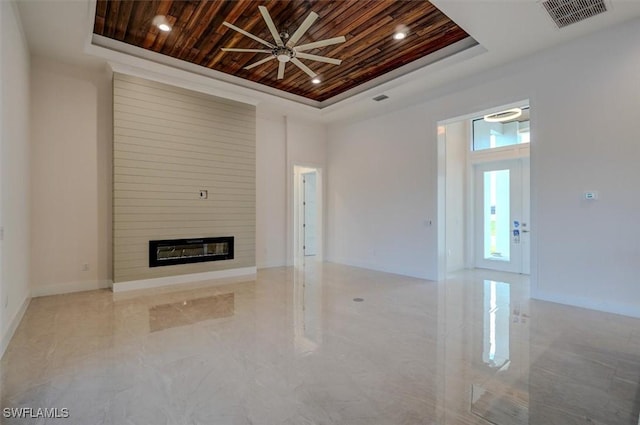 unfurnished living room with a tray ceiling, ceiling fan, a fireplace, and wooden ceiling