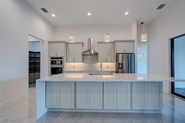 kitchen with gray cabinetry, sink, wall chimney exhaust hood, decorative light fixtures, and stainless steel appliances