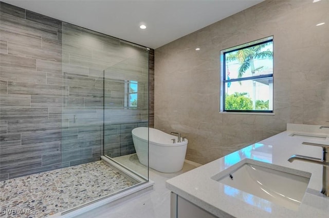 bathroom with vanity, separate shower and tub, and tile walls