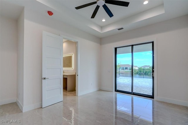 unfurnished room with ceiling fan and a raised ceiling