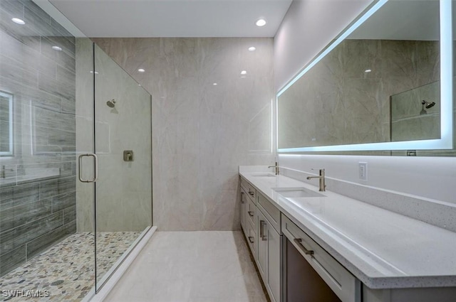 bathroom with vanity, a shower with door, and tile walls