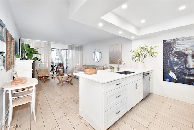 kitchen with sink, light hardwood / wood-style flooring, stainless steel dishwasher, kitchen peninsula, and white cabinets