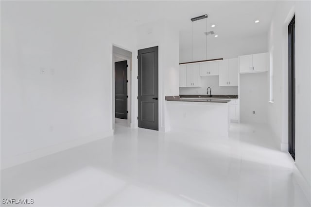 kitchen featuring hanging light fixtures, sink, and white cabinets