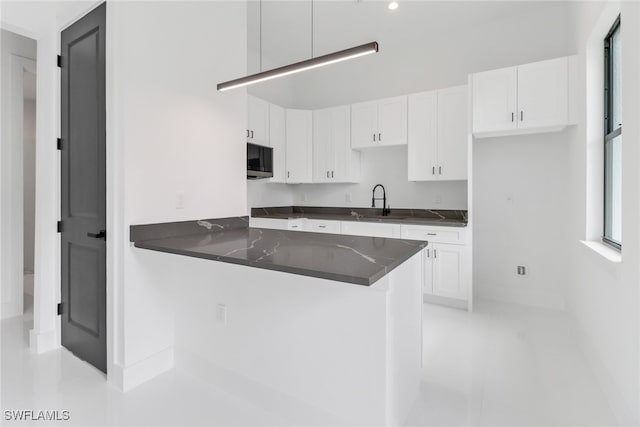 kitchen with white cabinetry, sink, and kitchen peninsula