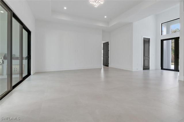 unfurnished room featuring a high ceiling, a raised ceiling, and french doors