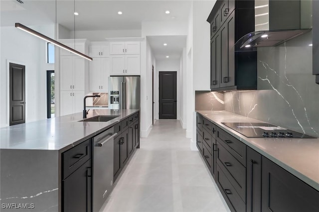 kitchen with appliances with stainless steel finishes, white cabinetry, sink, a large island, and wall chimney exhaust hood