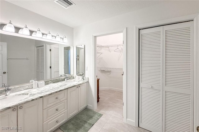 bathroom with tile patterned floors, vanity, and a textured ceiling