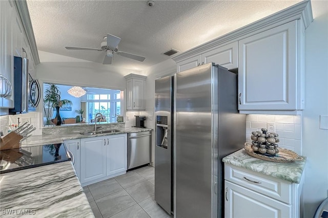 kitchen featuring backsplash, a textured ceiling, stainless steel appliances, ceiling fan, and sink