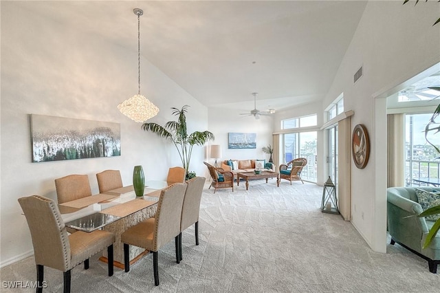 dining room with ceiling fan, light carpet, and high vaulted ceiling