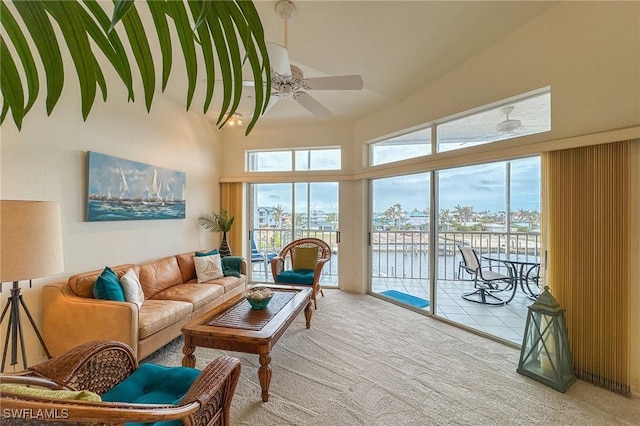 living room with light carpet, a water view, and ceiling fan