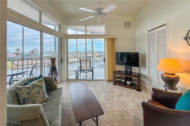 carpeted living room with ceiling fan and a high ceiling